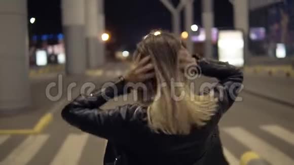 在城市里一个年轻漂亮的女人在一条空荡荡的马路上自由行走金发女孩微笑着摆姿势视频的预览图