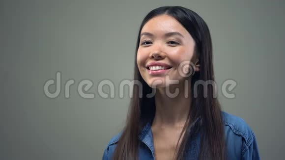 微笑的亚洲女人享受巧克力的味道站在灰色的背景上视频的预览图