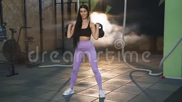 年轻的健身女子在健身房里做深蹲动作里拿着重量视频的预览图