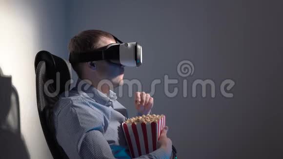 一个年轻人手里拿着一盒爆米花戴着虚拟现实耳机看视频视频的预览图