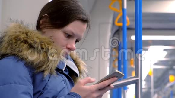 疲惫的女人坐在空的地铁车上浏览她的智能手机的肖像侧视视频的预览图