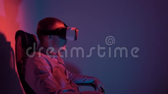 一个穿衬衫的年轻人坐在椅子上使用虚拟现实耳机视频的预览图