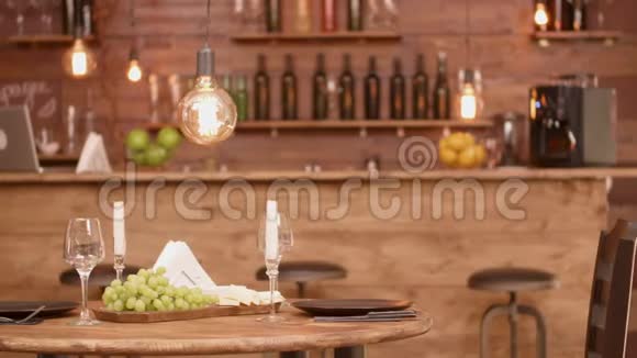 一张木制圆桌放在空餐厅里面有奶酪和葡萄开胃菜视频的预览图