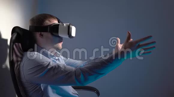 一个戴着虚拟现实耳机的年轻人坐在烟雾弥漫的房间中间的椅子上挥动着他的双手视频的预览图