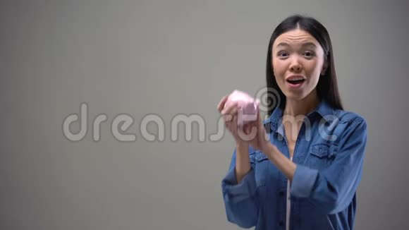 幸福的女孩手里拿着储蓄罐象征着节俭为储蓄提供银行服务视频的预览图