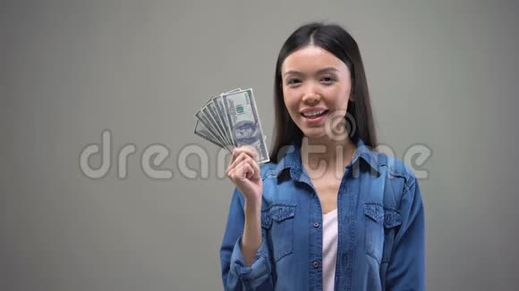 幸福的年轻女士拿着一美元钞票想着购物或度假视频的预览图