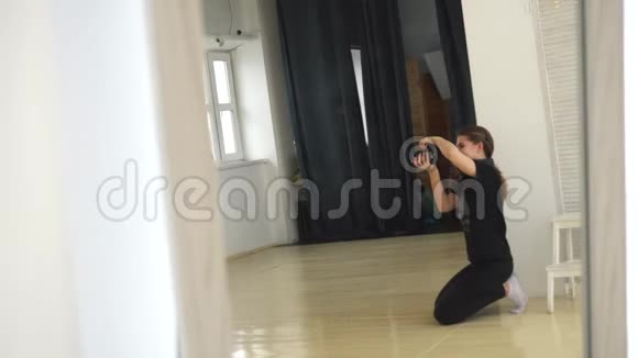 年轻的女摄影师穿着黑色的衣服坐在地板上在专业的摄影棚里拍照媒体视频的预览图