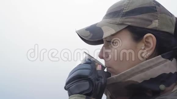 一位身穿军用迷彩服的美女在秋雾中从河底的金属杯中喝热茶视频的预览图