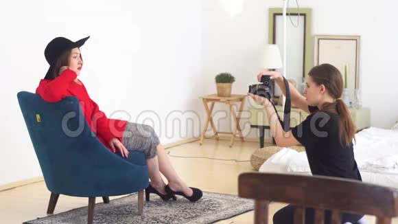 专业摄影棚里年轻漂亮的摄影师为戴黑帽子和穿红衣服的模特拍照特写视频的预览图
