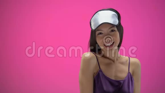 年轻的亚洲女人调情戴着眼罩被隔离在粉红色的背景上视频的预览图