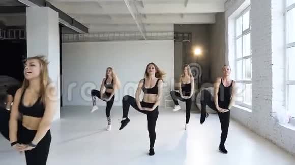 一群年轻女性在健身中心进行阶梯有氧运动漂亮的健身女孩一起做运动视频的预览图
