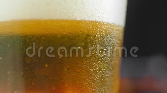 宏观拍摄的一个啤酒杯与冷啤酒气泡上升的玻璃慢动作啤酒气泡视频的预览图