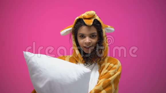 穿着长颈鹿睡衣的可爱疲惫的女人打呵欠睡在枕头上晚上视频的预览图