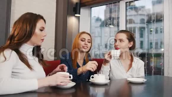 朋友们在酒吧见面三个年轻女人在聊天喝茶视频的预览图