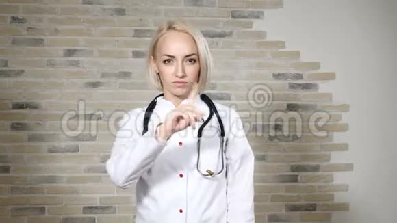 金发女医生的肖像戴着白色的医用衣服显示出不赞成的迹象强国视频的预览图