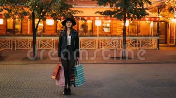 年轻女性购物狂在街上站着手里拿着购物袋一边看着镜头视频的预览图