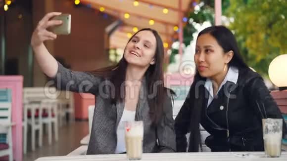 快乐的女性朋友正在用智能手机进行在线视频通话看着屏幕坐在街上聊天视频的预览图