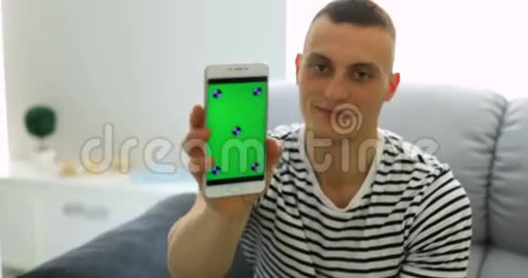 男人在家里展示绿色智能手机屏幕视频的预览图