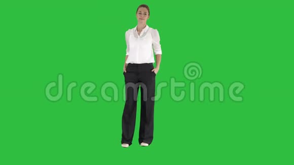 迷人的微笑女商人站着双臂交叉看着绿色屏幕上的相机Chroma键视频的预览图