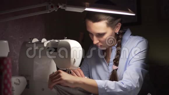 女人用灯把衣服缝在缝纫机上时尚创造和剪裁视频的预览图