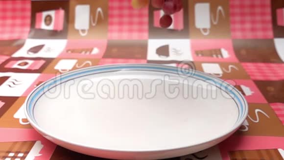 一串串的葡萄掉进桌子上的一个白色盘子里视频的预览图
