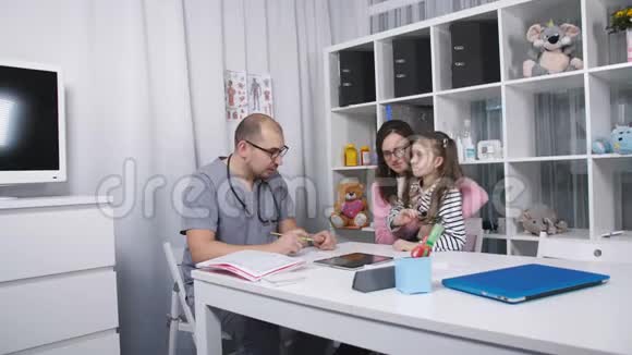 友好的医生和病人妈妈和她的女儿交谈她办公室里的医生检查了一下喉咙痛视频的预览图
