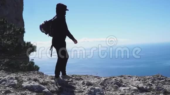 游客背着背包在海上的高山上漫步视频的预览图