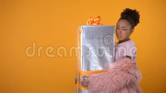 令人惊讶的女人拿着大礼品盒上门送货服务黄色背景视频的预览图