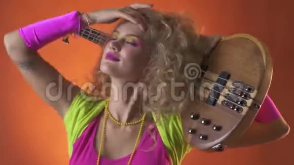 穿着复古服装的金发女人肩上扛着吉他跳舞摆姿势视频的预览图