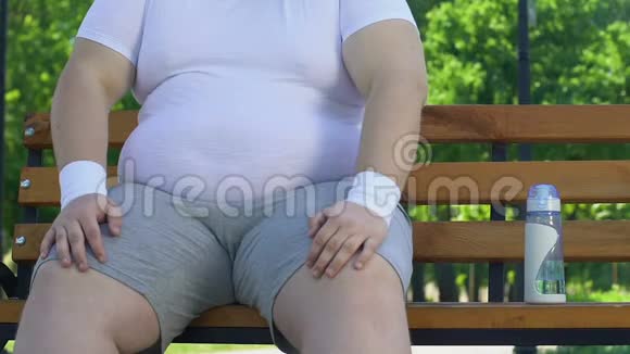 懒汉坐在长凳上抚摸着他的大胖肚子而不是去运动视频的预览图
