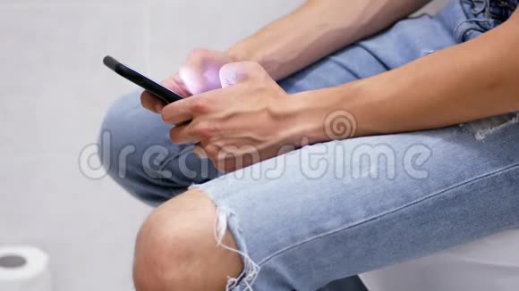 男厕所里拿着电话的手的特写镜头男人在厕所里用智能手机视频的预览图