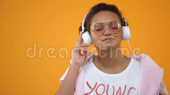 年轻时尚女性在耳机里欣赏最喜欢的音乐收音机应用程序视频的预览图