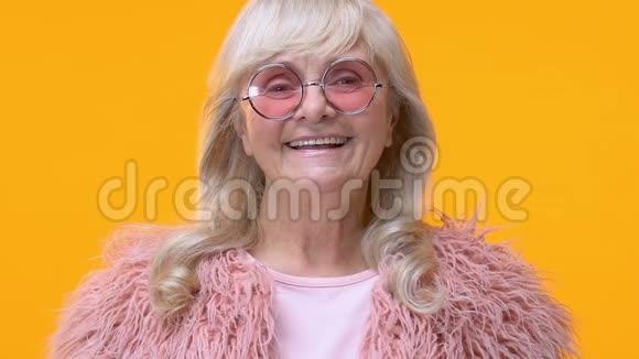 现代老妇人戴着粉红色眼镜黄色背景上带着微笑相机魅力四射视频的预览图