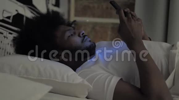 夜间在床上使用智能手机的非洲人视频的预览图