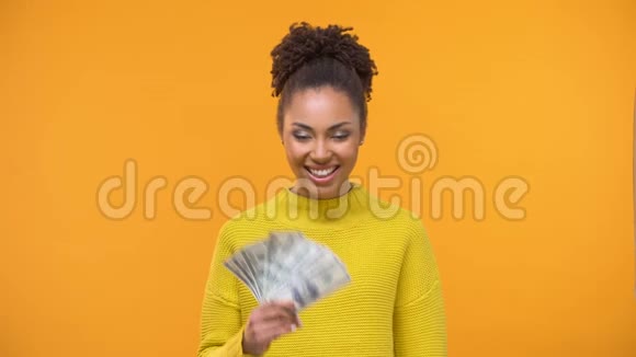 漂亮的黑人女士拿着一堆美元和信用卡在线支付视频的预览图