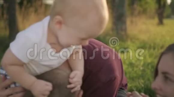 有第一个孩子的欧洲家庭在夏天坐在绿色公园里玩得很开心视频的预览图