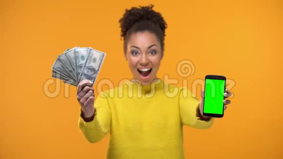 非洲裔美国妇女展示智能手机和一堆美元汇款视频的预览图