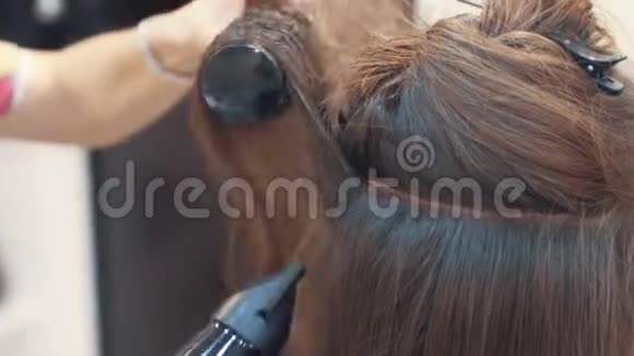 关闭理发师用吹风机将女性湿发擦干后剪下慢动作视频的预览图