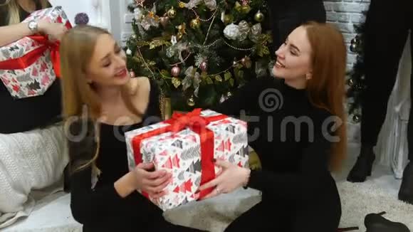 两个年轻的女模特坐在面粉上手里拿着一个红色丝带的大节日盒子送礼物快乐视频的预览图