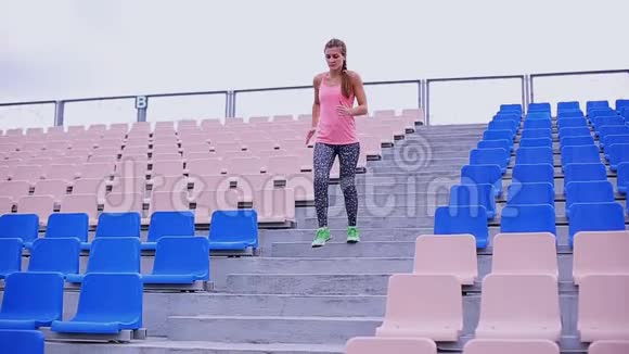 漂亮的肌肉女孩在体育场的楼梯上跑来跑去交叉健身健身健康的生活方式视频的预览图