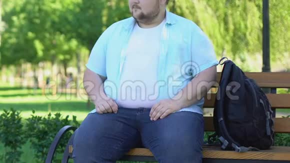 有趣的胖男人坐在公园的长凳上好奇地看着路人视频的预览图