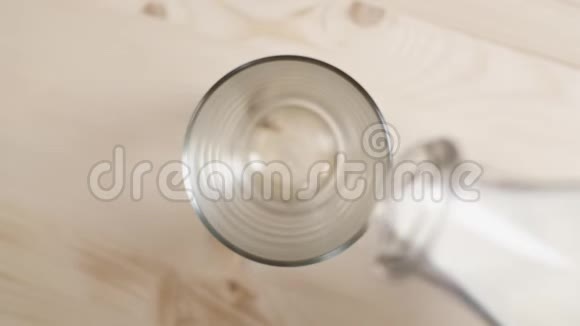 把牛奶倒在木桌上的玻璃杯里把从透明瓶子里倒出来的牛奶合上视频的预览图