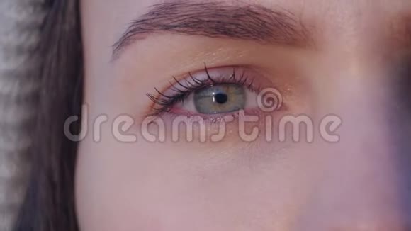 一个年轻美丽的女人的绿色眼睛看着相机在夕阳的光线下缓慢的动作闭上眼睛视频的预览图