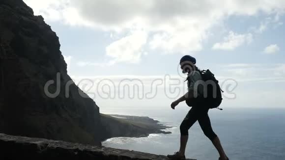带背垫的男性徒步旅行者正走在大洋上方加那利群岛上的一条路的边缘视频的预览图