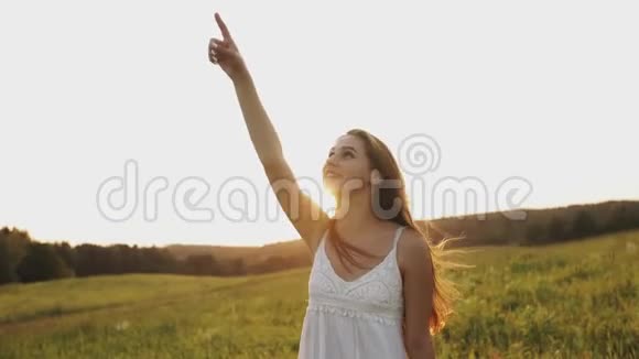 快乐的年轻女子在田野里微笑笑着用手在天空和飞机上表演视频的预览图