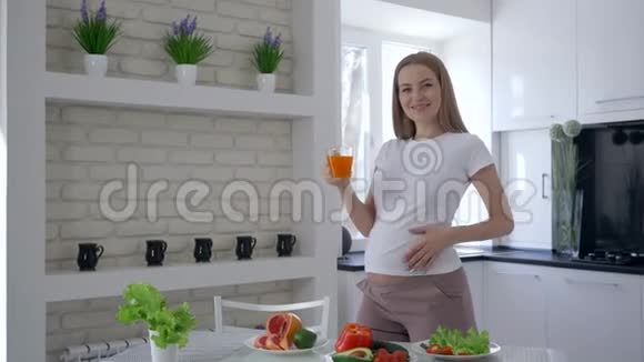 孕期维生素健康早餐时肚子大的快乐孕妇喝新鲜果汁视频的预览图