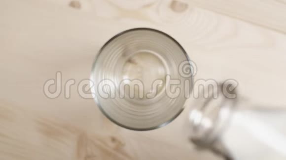 把牛奶倒在木桌上的玻璃杯里把从透明瓶子里倒出来的牛奶合上视频的预览图