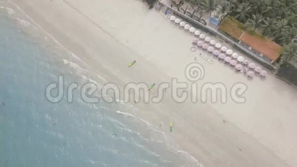 度假酒店海滩上的鸟瞰伞和在蓝海游泳的人们在度假海滩上休息的游客视频的预览图