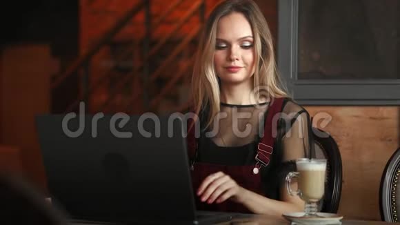 专心致志的女士戴着耳机坐在桌旁手提电脑看屏幕做笔记学习外语视频的预览图