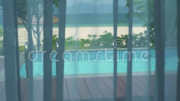 从窗户观看游泳池和海边的窗帘带游泳池蓝海和海滩的豪华别墅视频的预览图
